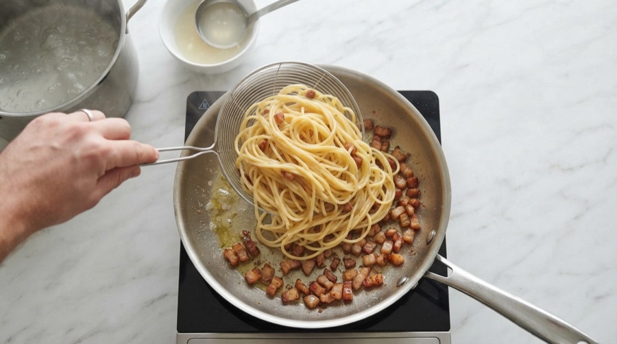 Carbonara preparation: cooking the spaghetti and adding it to the guanciale